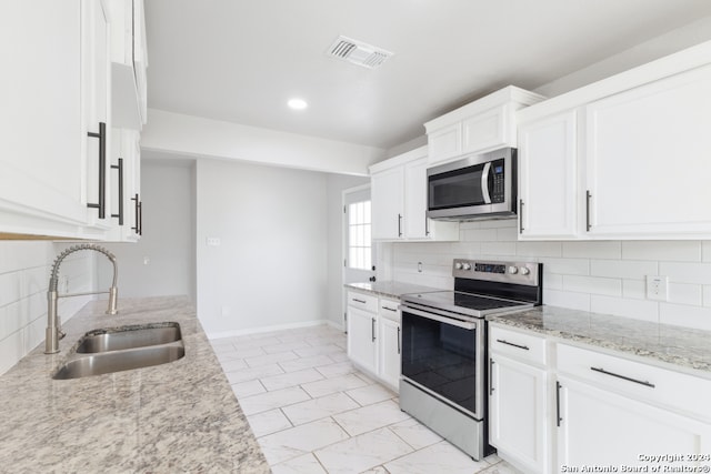 kitchen featuring stainless steel appliances, light stone countertops, sink, and white cabinetry