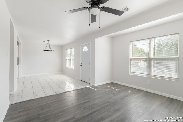 entryway with ceiling fan with notable chandelier, hardwood / wood-style flooring, and a wealth of natural light