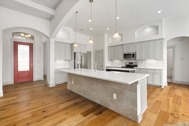 kitchen featuring appliances with stainless steel finishes, decorative light fixtures, light hardwood / wood-style floors, and backsplash