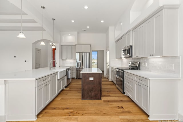 kitchen with stainless steel appliances, a large island, light hardwood / wood-style flooring, and beam ceiling