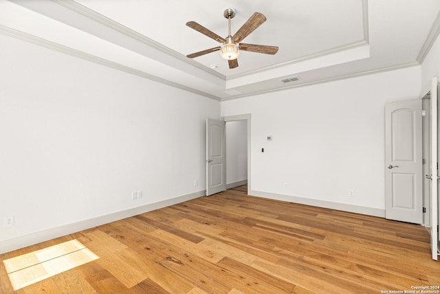 spare room featuring a raised ceiling, wood-type flooring, ornamental molding, and ceiling fan