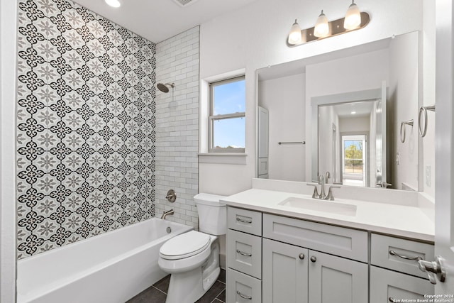 full bathroom with tile patterned flooring, tiled shower / bath combo, vanity, and toilet