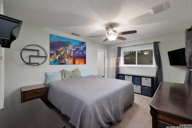 carpeted bedroom featuring ceiling fan and a textured ceiling