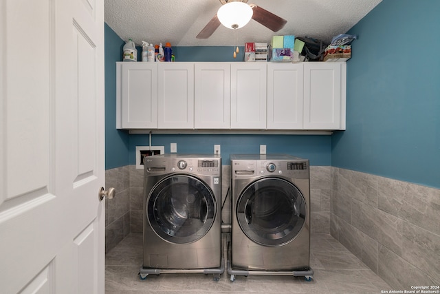 laundry area featuring ceiling fan, washing machine and clothes dryer, cabinets, and a textured ceiling