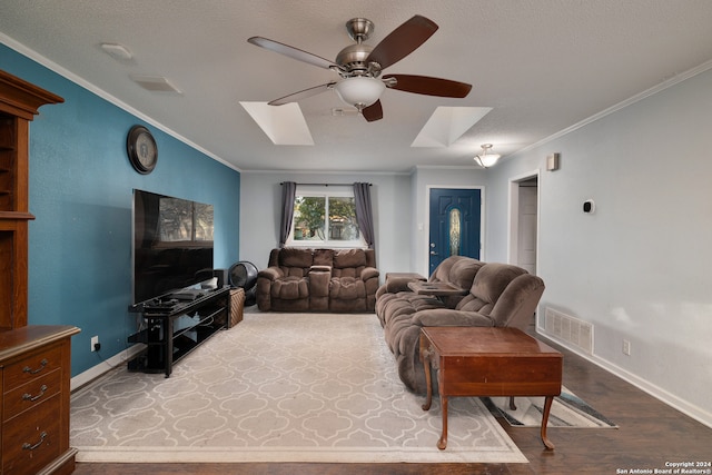 living room with ceiling fan, a skylight, crown molding, and hardwood / wood-style flooring