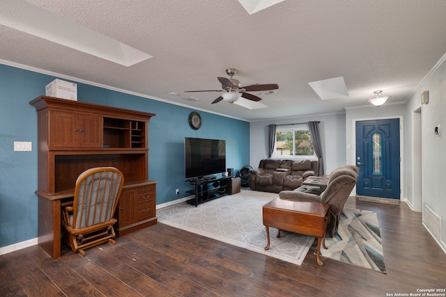 living room with ceiling fan, a skylight, ornamental molding, a textured ceiling, and dark wood-type flooring