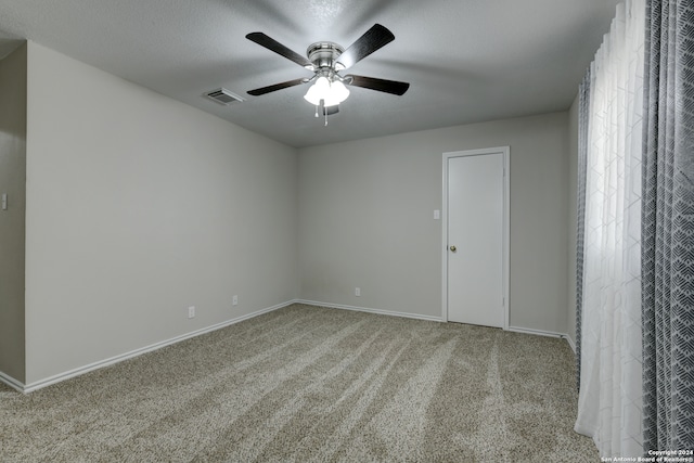 empty room featuring light carpet, ceiling fan, and a textured ceiling