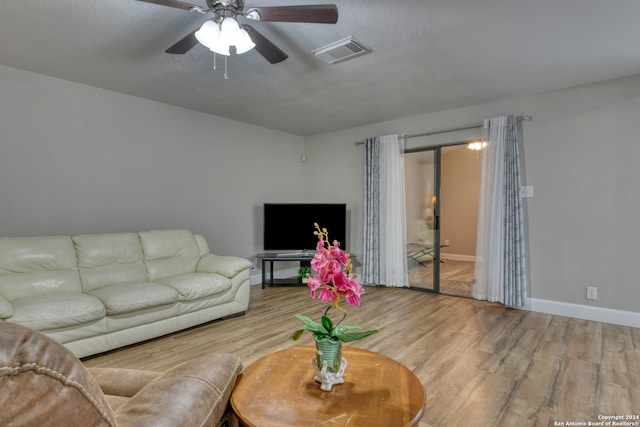 living room featuring ceiling fan, a textured ceiling, and light hardwood / wood-style flooring