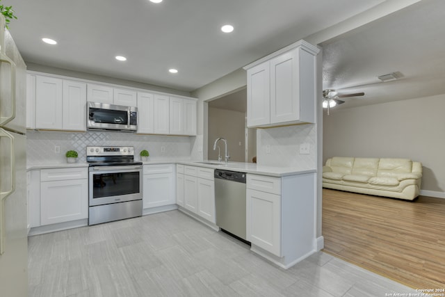 kitchen with decorative backsplash, appliances with stainless steel finishes, sink, and white cabinetry