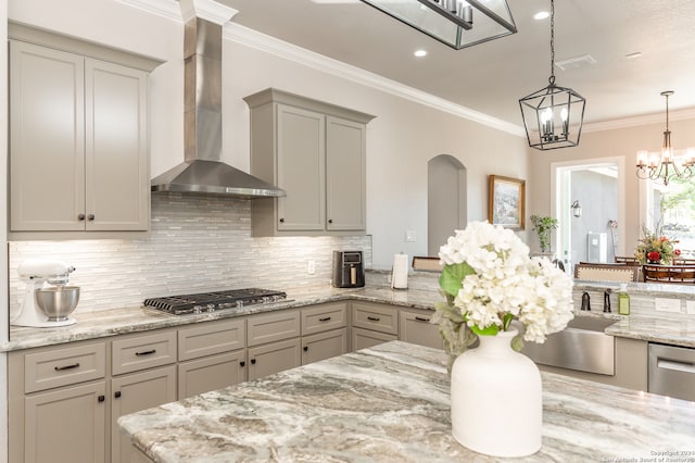 kitchen with appliances with stainless steel finishes, gray cabinets, light stone countertops, and wall chimney range hood