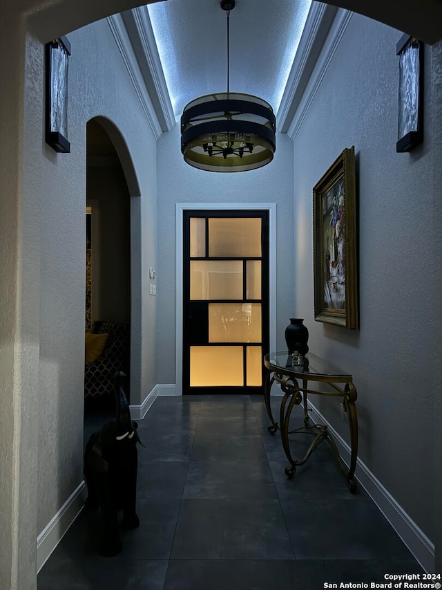 corridor with lofted ceiling, crown molding, and a notable chandelier