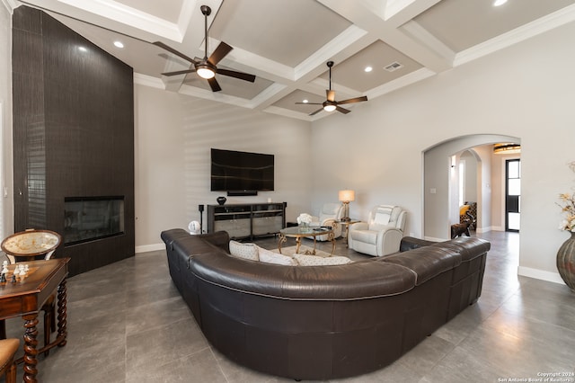 living room with ceiling fan, crown molding, beam ceiling, coffered ceiling, and a fireplace