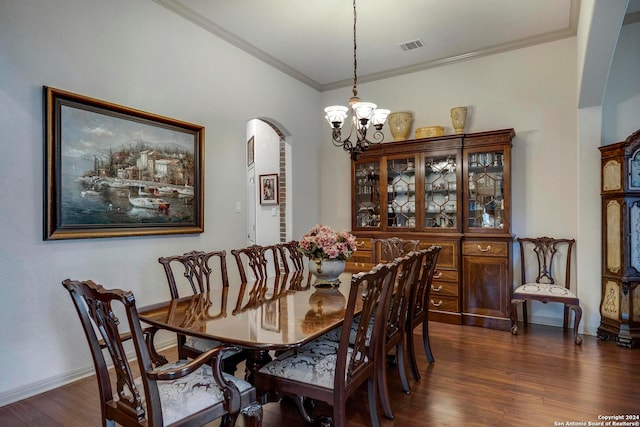 dining space featuring dark hardwood / wood-style floors, crown molding, and a chandelier