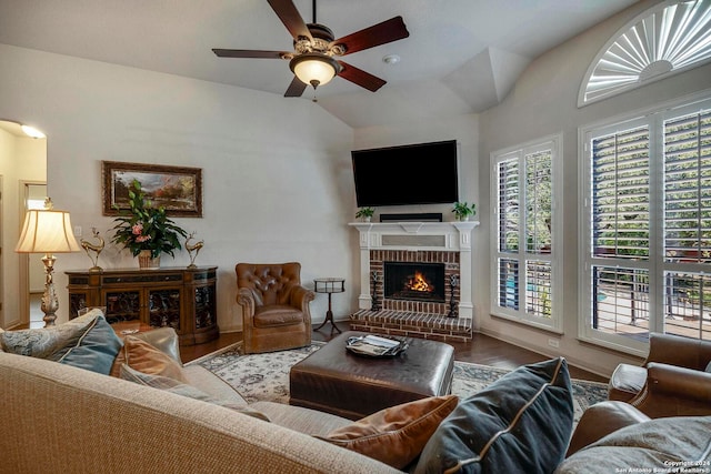 living room with ceiling fan, hardwood / wood-style flooring, a fireplace, and vaulted ceiling