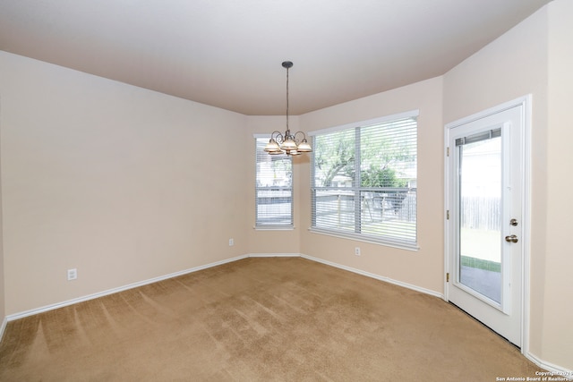 carpeted empty room featuring a notable chandelier and a healthy amount of sunlight