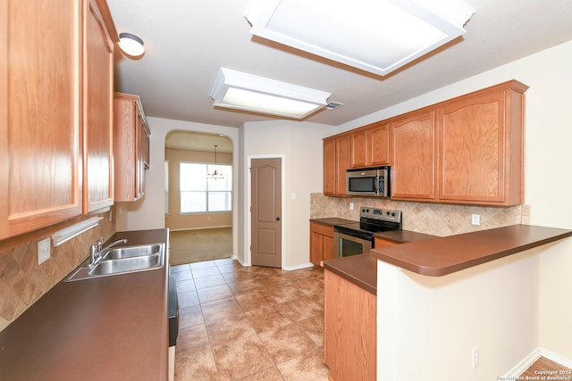 kitchen with stainless steel appliances, tasteful backsplash, sink, kitchen peninsula, and light tile patterned floors