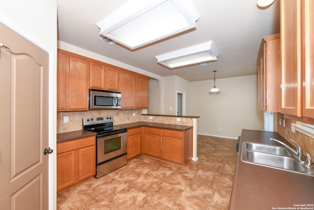 kitchen with hanging light fixtures, sink, kitchen peninsula, backsplash, and appliances with stainless steel finishes