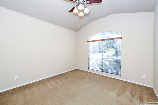 carpeted spare room featuring vaulted ceiling and ceiling fan