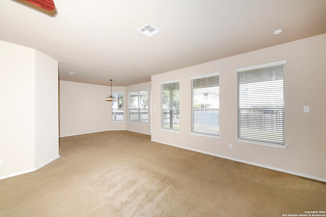 empty room featuring light colored carpet and a notable chandelier