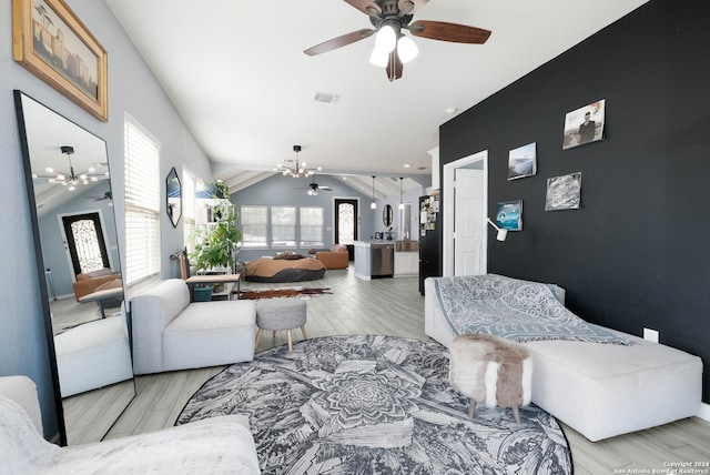 living room featuring ceiling fan with notable chandelier, light hardwood / wood-style floors, and vaulted ceiling