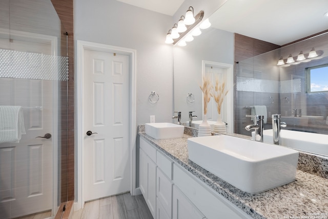 bathroom with hardwood / wood-style floors, vanity, and tiled shower