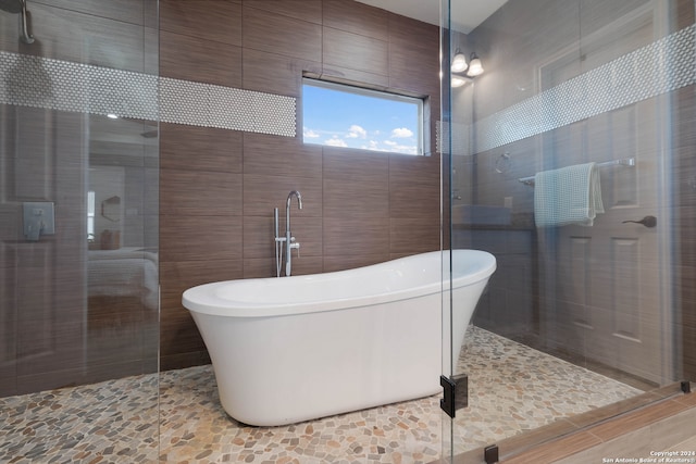 bathroom featuring tile walls and independent shower and bath