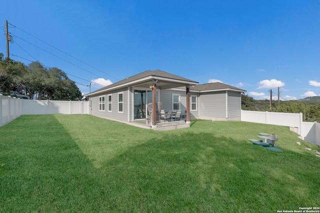 rear view of property featuring ceiling fan, a lawn, and a patio area