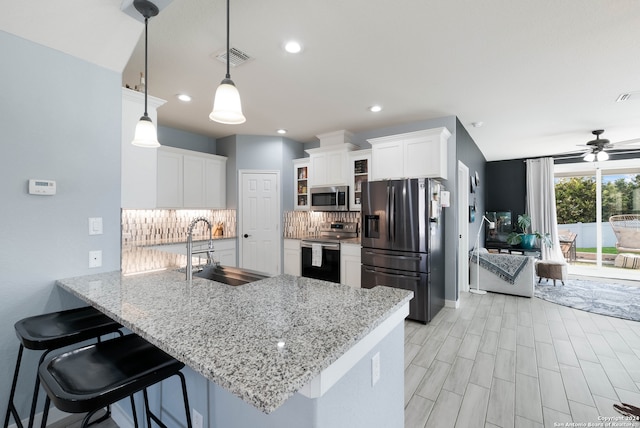 kitchen featuring sink, kitchen peninsula, hanging light fixtures, white cabinets, and appliances with stainless steel finishes