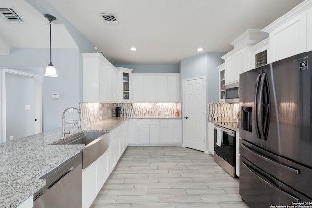 kitchen with light stone countertops, decorative backsplash, stainless steel appliances, white cabinets, and hanging light fixtures