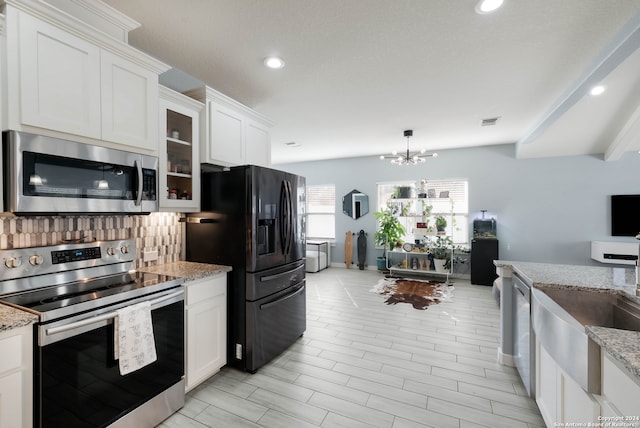 kitchen with light stone counters, white cabinets, a chandelier, appliances with stainless steel finishes, and decorative backsplash