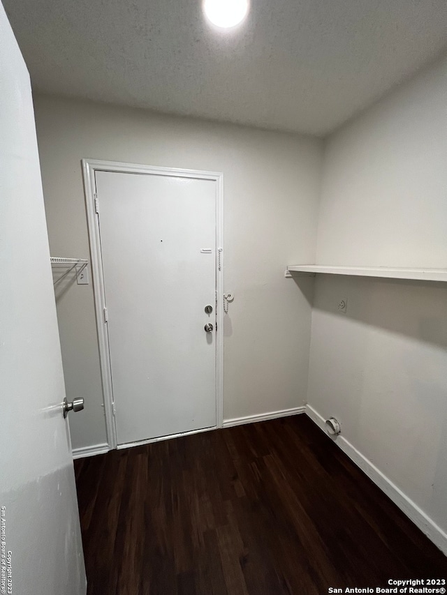 clothes washing area with dark hardwood / wood-style flooring and a textured ceiling