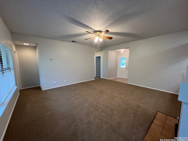 spare room featuring ceiling fan, a textured ceiling, and dark colored carpet