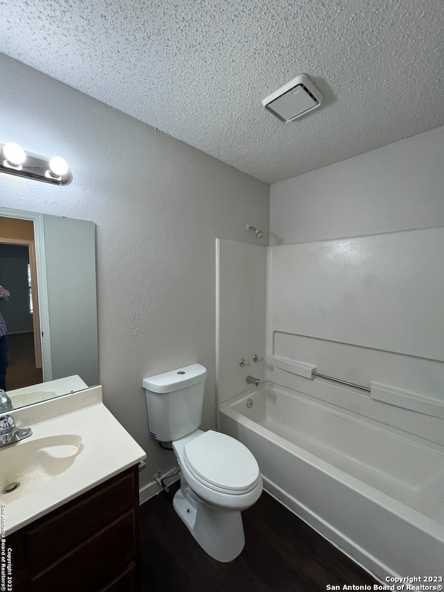 full bathroom with toilet, hardwood / wood-style floors, bathing tub / shower combination, vanity, and a textured ceiling