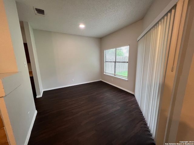 unfurnished room with a textured ceiling and dark hardwood / wood-style floors