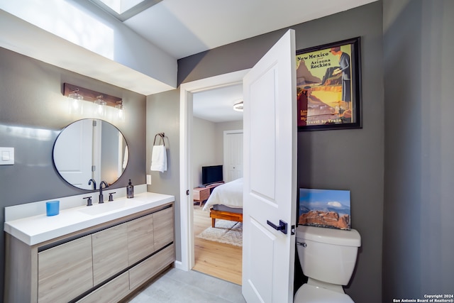 bathroom with toilet, vanity, and wood-type flooring