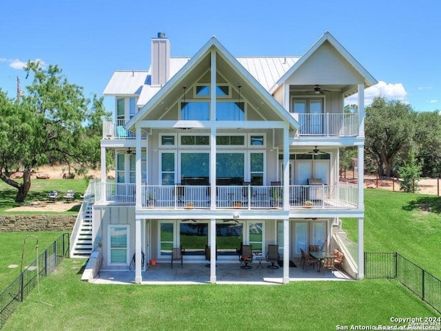 rear view of property featuring a yard, ceiling fan, a balcony, and a patio area