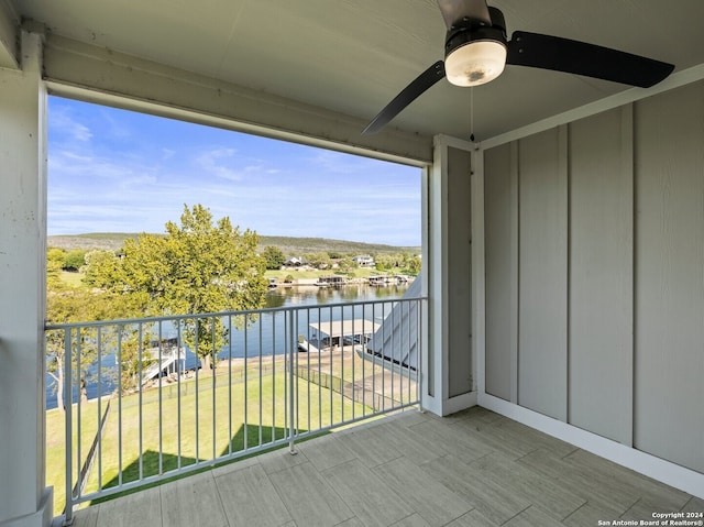 balcony featuring a water view and ceiling fan