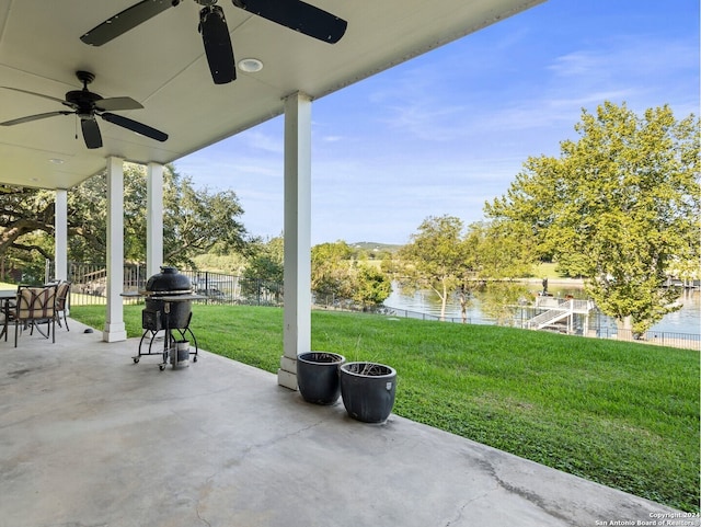 view of patio with ceiling fan, area for grilling, and a water view