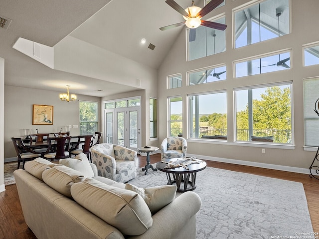 living room with wood-type flooring, ceiling fan with notable chandelier, and high vaulted ceiling