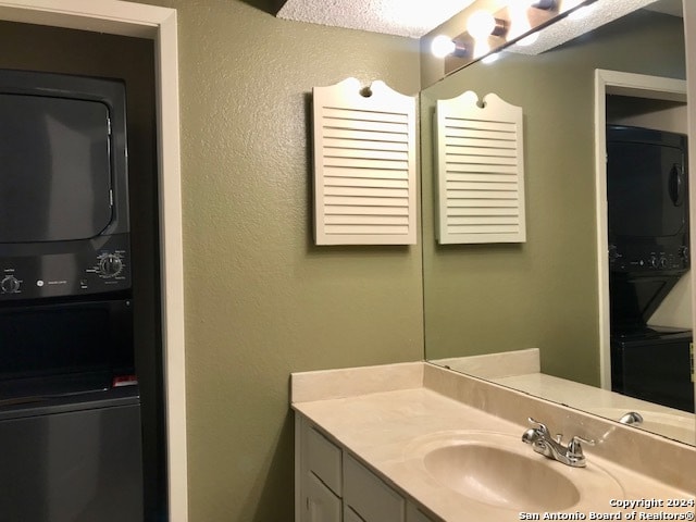 bathroom with sink, stacked washer / drying machine, and a textured ceiling