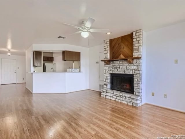 unfurnished living room featuring ceiling fan, light hardwood / wood-style flooring, and a fireplace