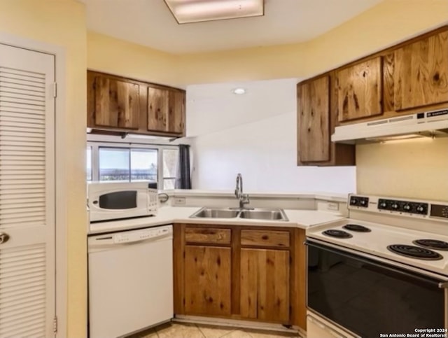 kitchen featuring light tile patterned flooring, white appliances, and sink