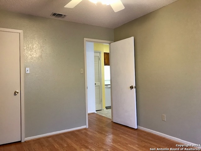 unfurnished bedroom featuring hardwood / wood-style flooring, a textured ceiling, and ceiling fan