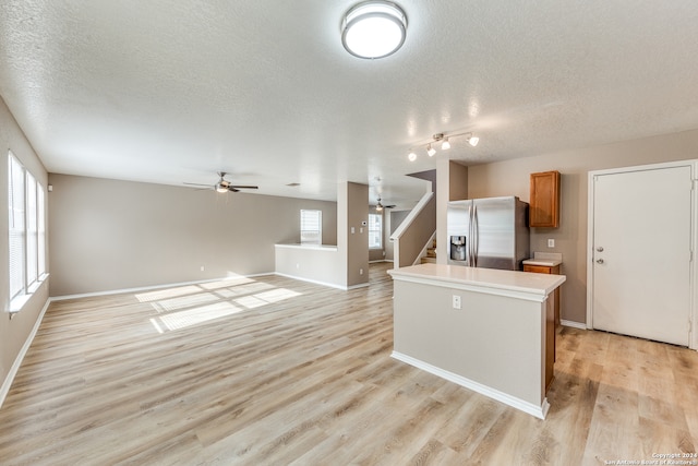 kitchen featuring stainless steel fridge, ceiling fan, light hardwood / wood-style floors, and a textured ceiling