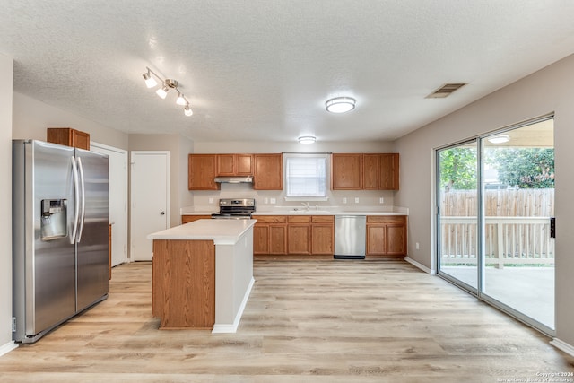 kitchen with sink, stainless steel appliances, light hardwood / wood-style floors, and a kitchen island