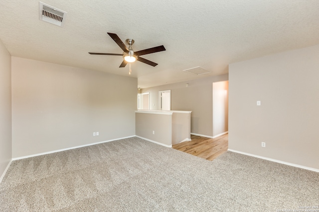 carpeted empty room with ceiling fan and a textured ceiling