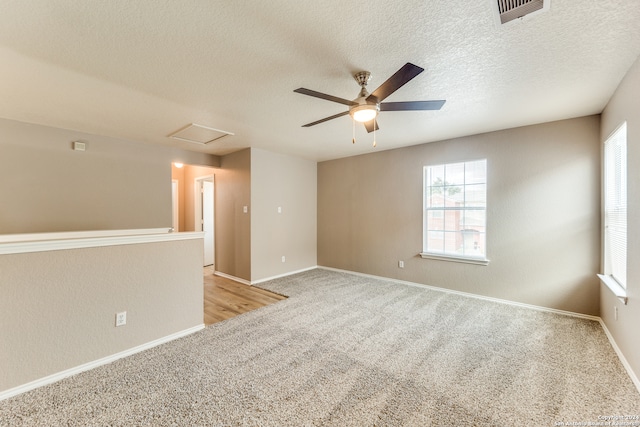 spare room featuring ceiling fan, light colored carpet, and a textured ceiling