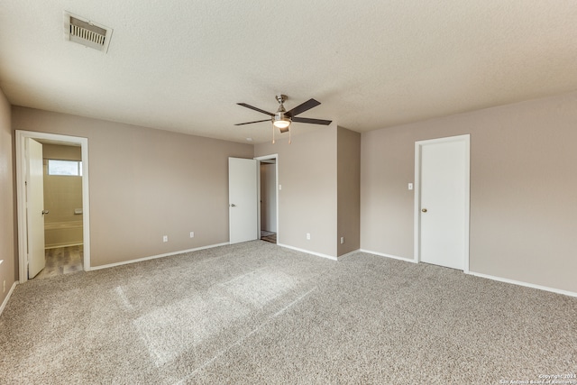 unfurnished bedroom featuring ensuite bathroom, ceiling fan, carpet, and a textured ceiling