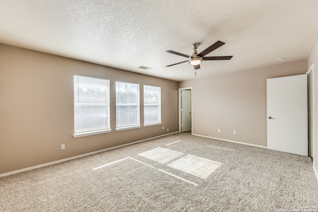 carpeted empty room featuring ceiling fan and a textured ceiling