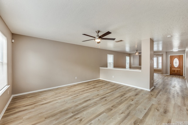 unfurnished living room featuring a textured ceiling, light wood-type flooring, and ceiling fan